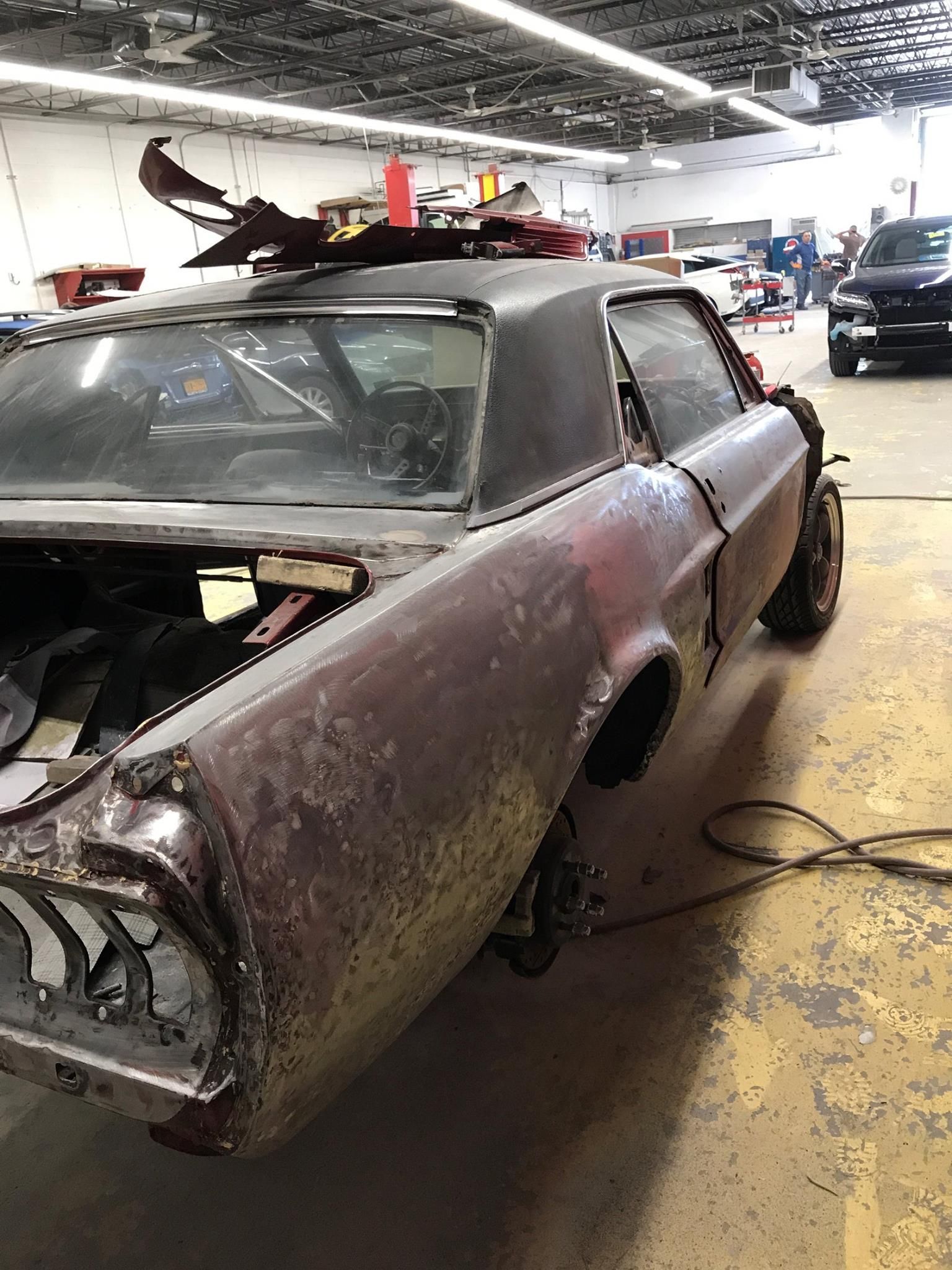 Classic maroon car undergoing restoration in a shop.