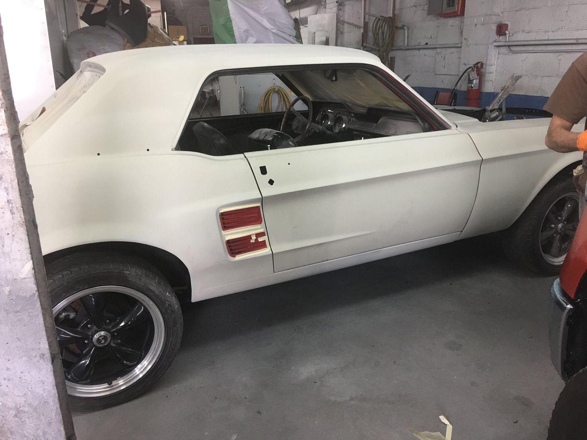 White classic Mustang car in a shop, being restored.