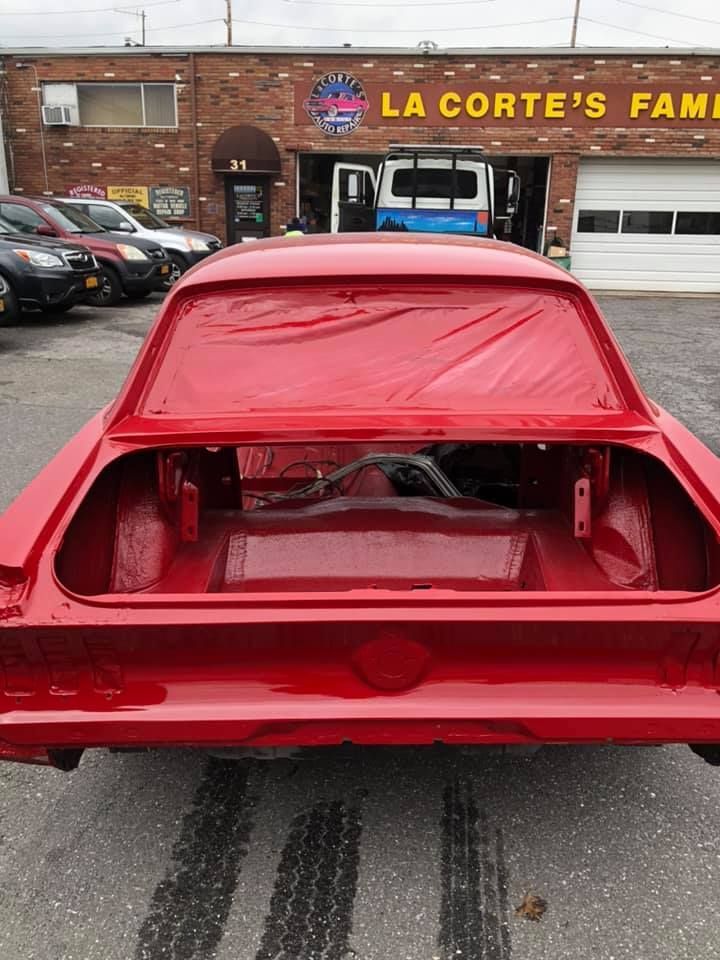 Red classic car trunk open, masked for painting at La Corte's Family Auto shop.