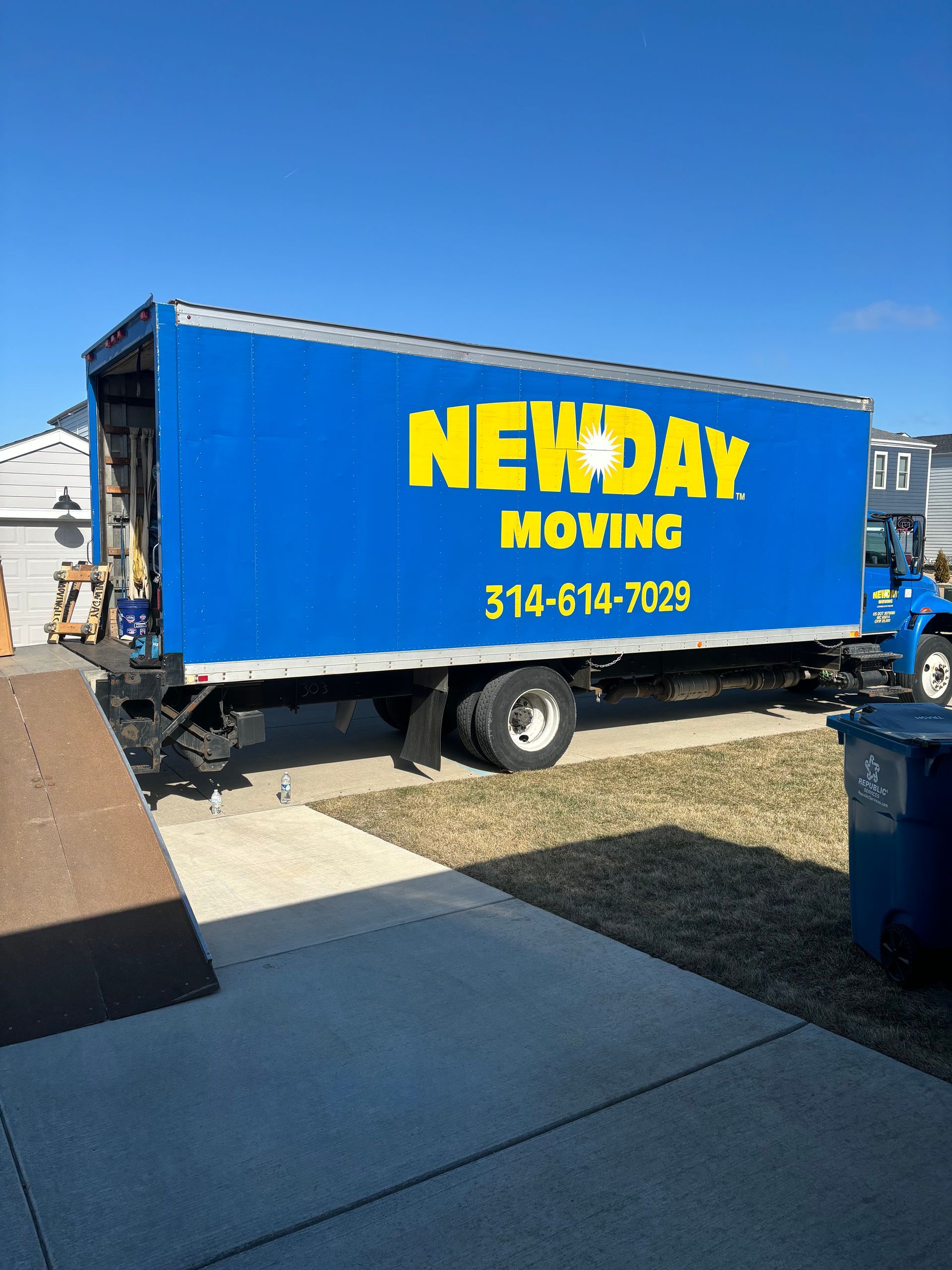 Blue NEXDAY MOVING truck parked outdoors under a clear sky