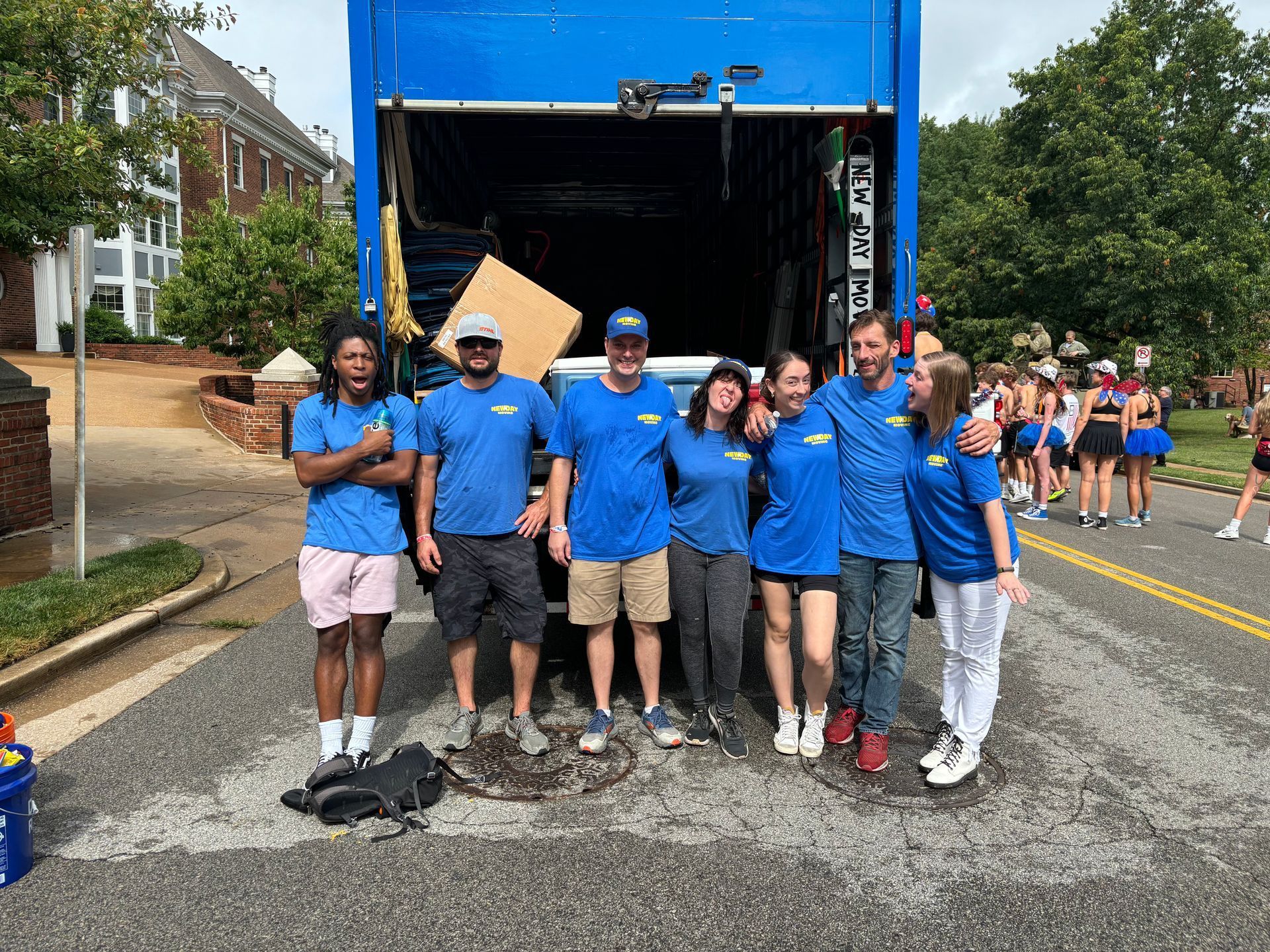 New Day Moving staff in blue shirts posing in front of a truck