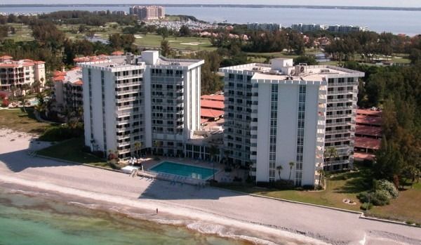 Beachfront high-rise condos beside a sandy shore and turquoise water