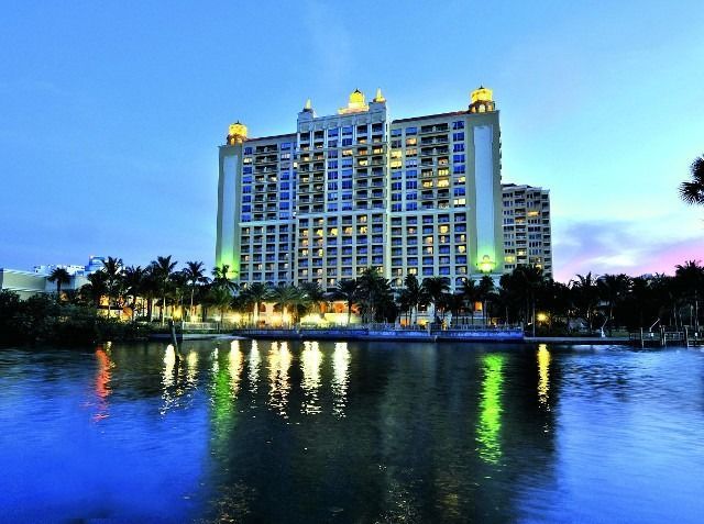 Lit hotel building at dusk reflected in a calm waterfront