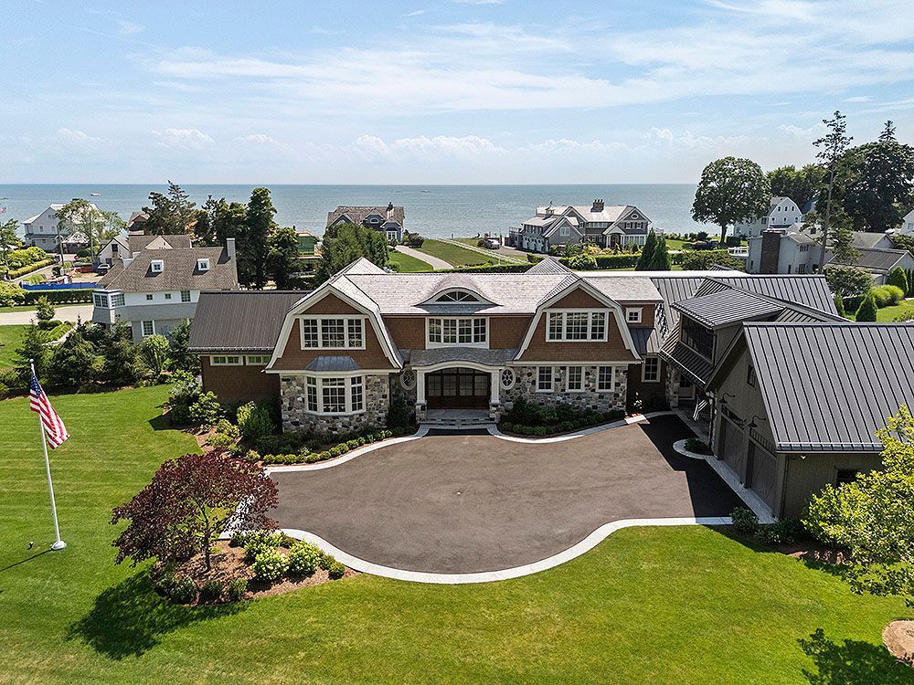 Large, luxurious home with a view of the ocean. A flag waves on the front lawn.
