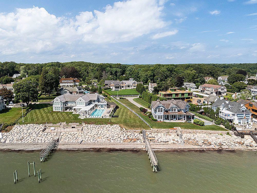 Coastal homes on a sunny day, overlooking the water, with docks and a shoreline of rocks.
