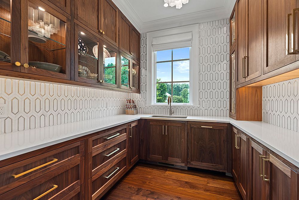 Dark wood pantry with white countertops, patterned backsplash, and a window.