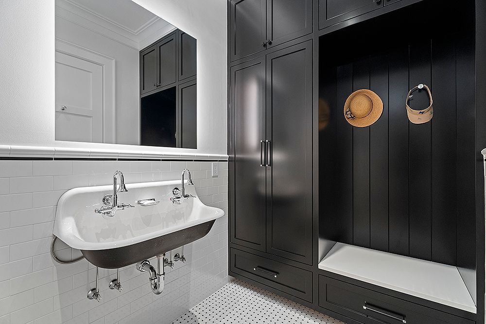 Black and white bathroom with a vintage sink, cabinets, and a small hat rack.