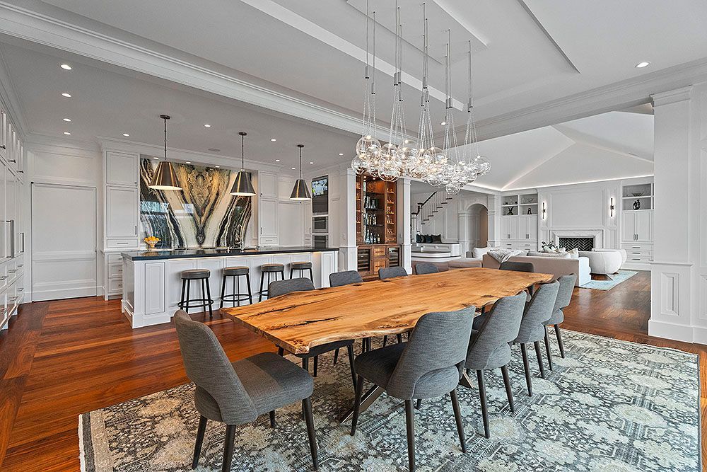 Formal dining room with long wooden table, gray chairs, and elaborate light fixture.