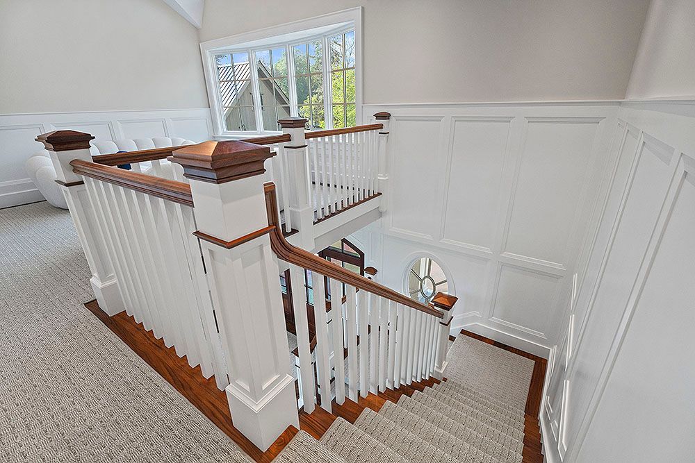 Downward view of a bright staircase with white railings and wooden accents.