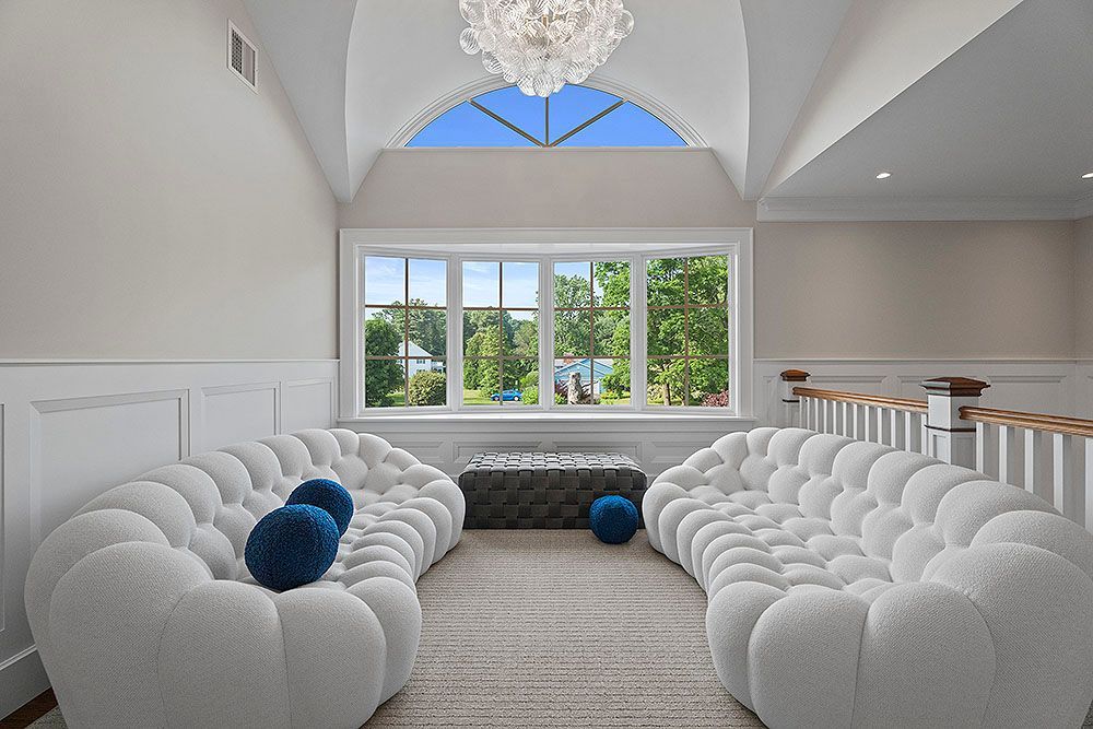 Two white bubble couches face a window, blue accents.