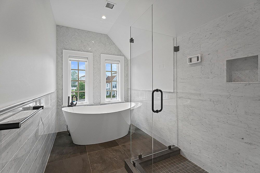 Bathroom with a modern design, features a bathtub near windows and a glass shower.