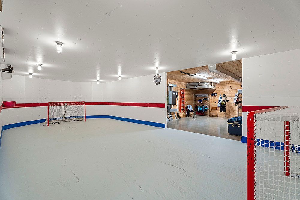 Indoor hockey rink with white ice, red and blue boards, and goals. A glimpse into a storage room is also visible.