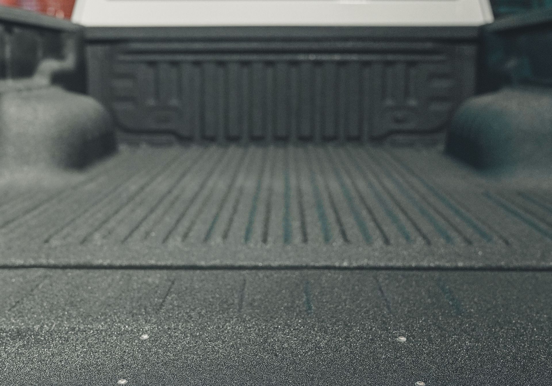 Empty black truck bed with textured liner and ribbed surface.