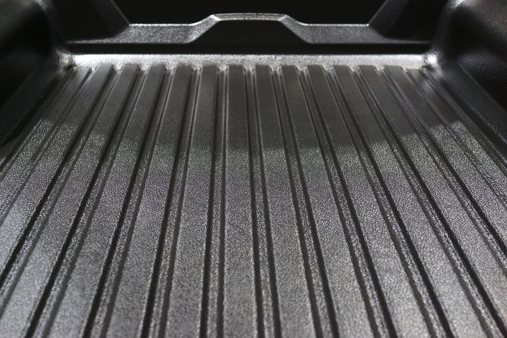 Black truck bed with textured surface and ribbed floor.