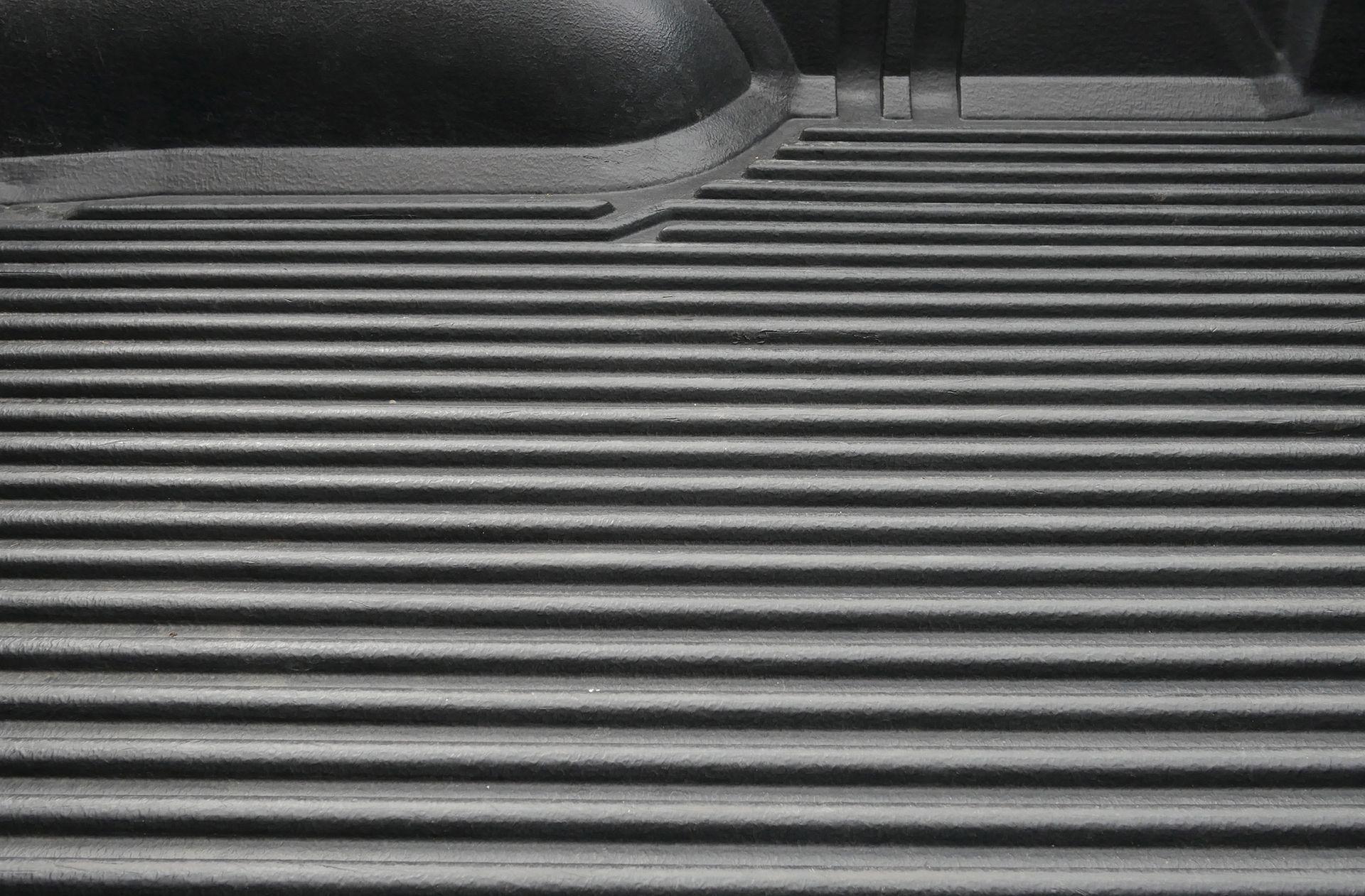 Black truck bed liner with horizontal ribbed texture.