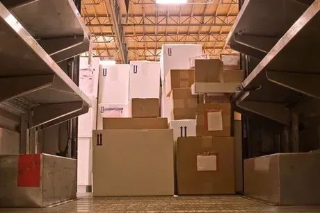 Interior of a mail truck filled with a variety of stacked cardboard boxes and shelving on either side.