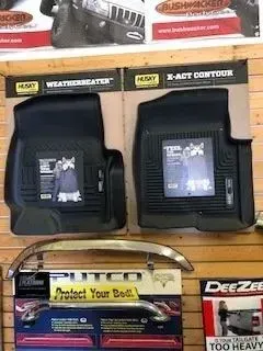 Floor mats and car accessories displayed on a wooden wall in a store.