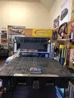 Black truck bed cover in a store display with a product box on top.
