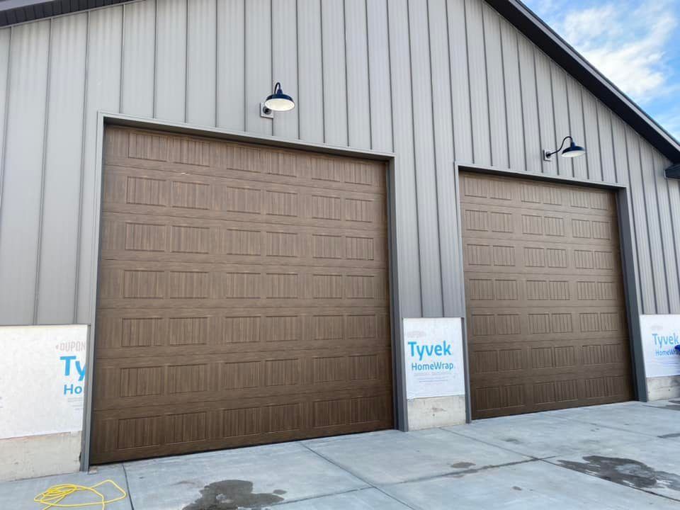 Two brown garage doors with lights on a building.