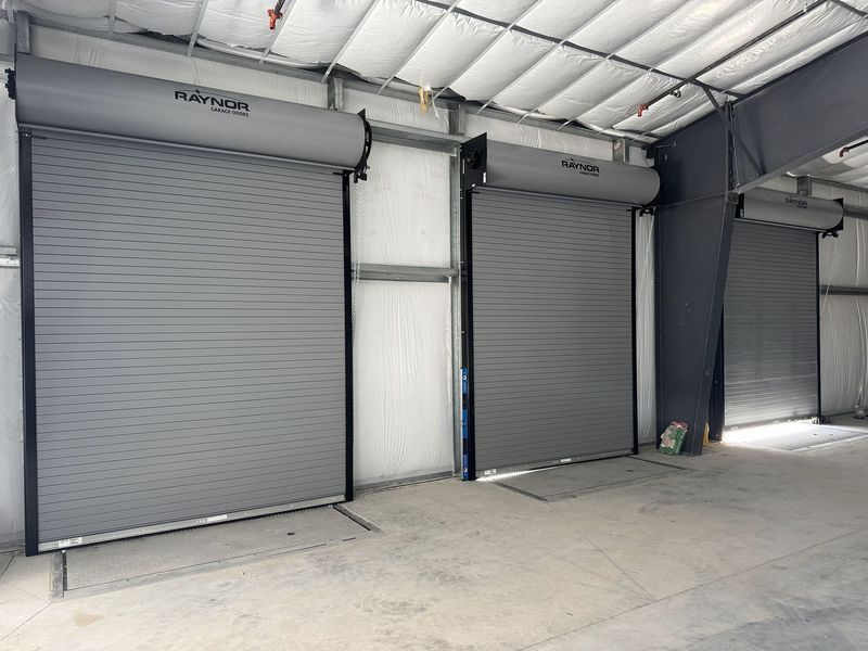Three closed gray roll-up doors in a warehouse.