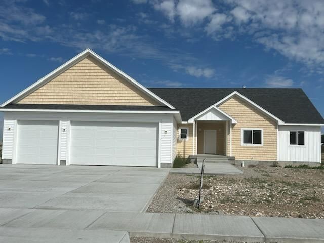 House with two-car garage, beige siding, white trim, and black roof against a blue sky.