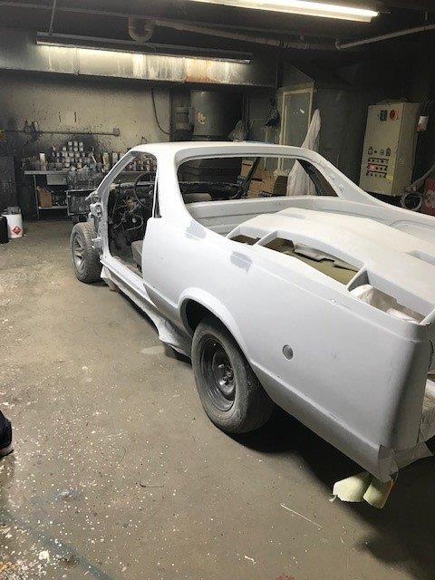 A white car is sitting in a garage with the door open