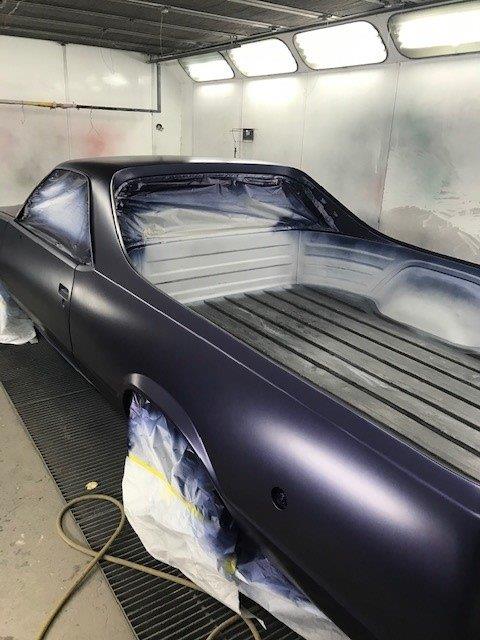 A purple car is being painted in a garage.
