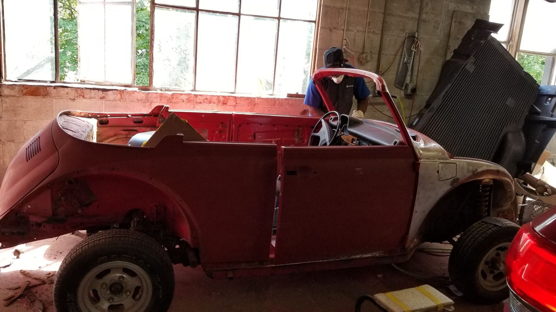 A red car is sitting in a garage with the hood open.