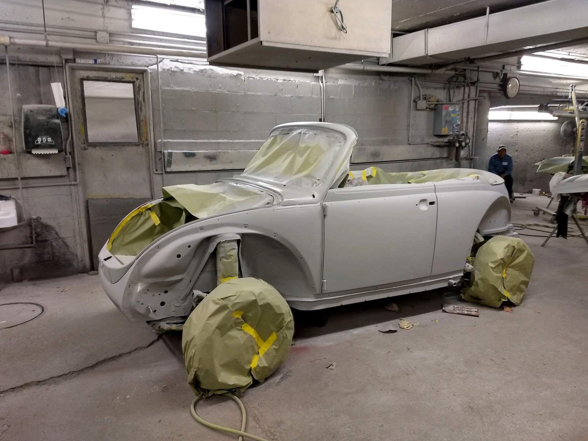 A white car is being painted in a garage.