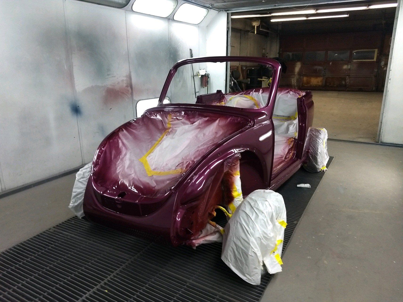A purple car is being painted in a garage.