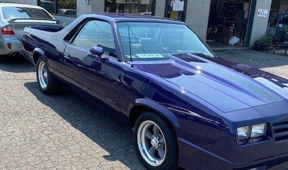 A purple car is parked in front of a building.