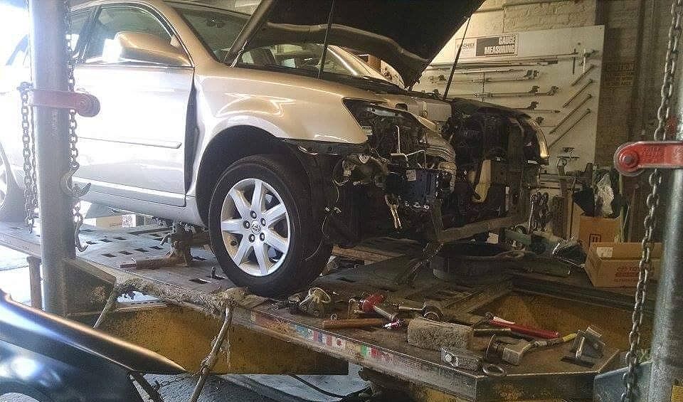 A car is being worked on in a garage with the hood open