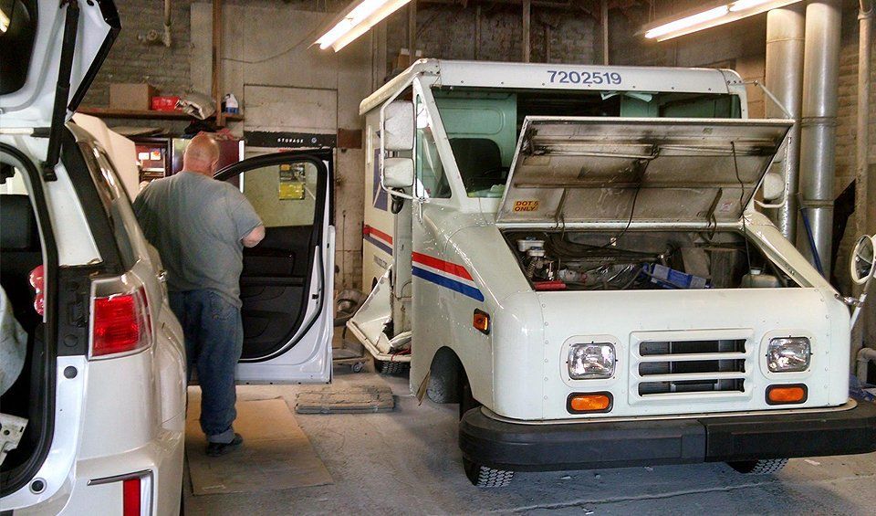 A man is working on a mail truck in a garage