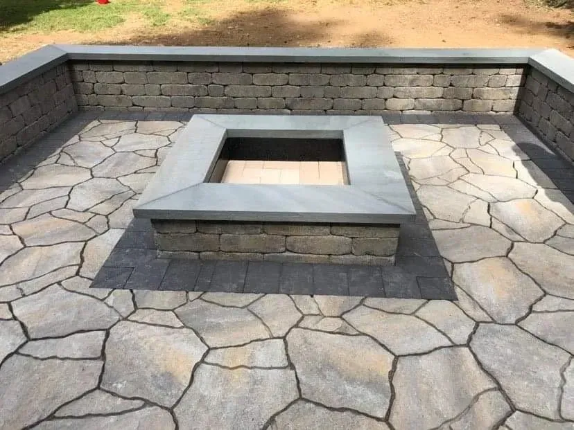 Stone patio with built-in fire pit, surrounded by a low stone wall.