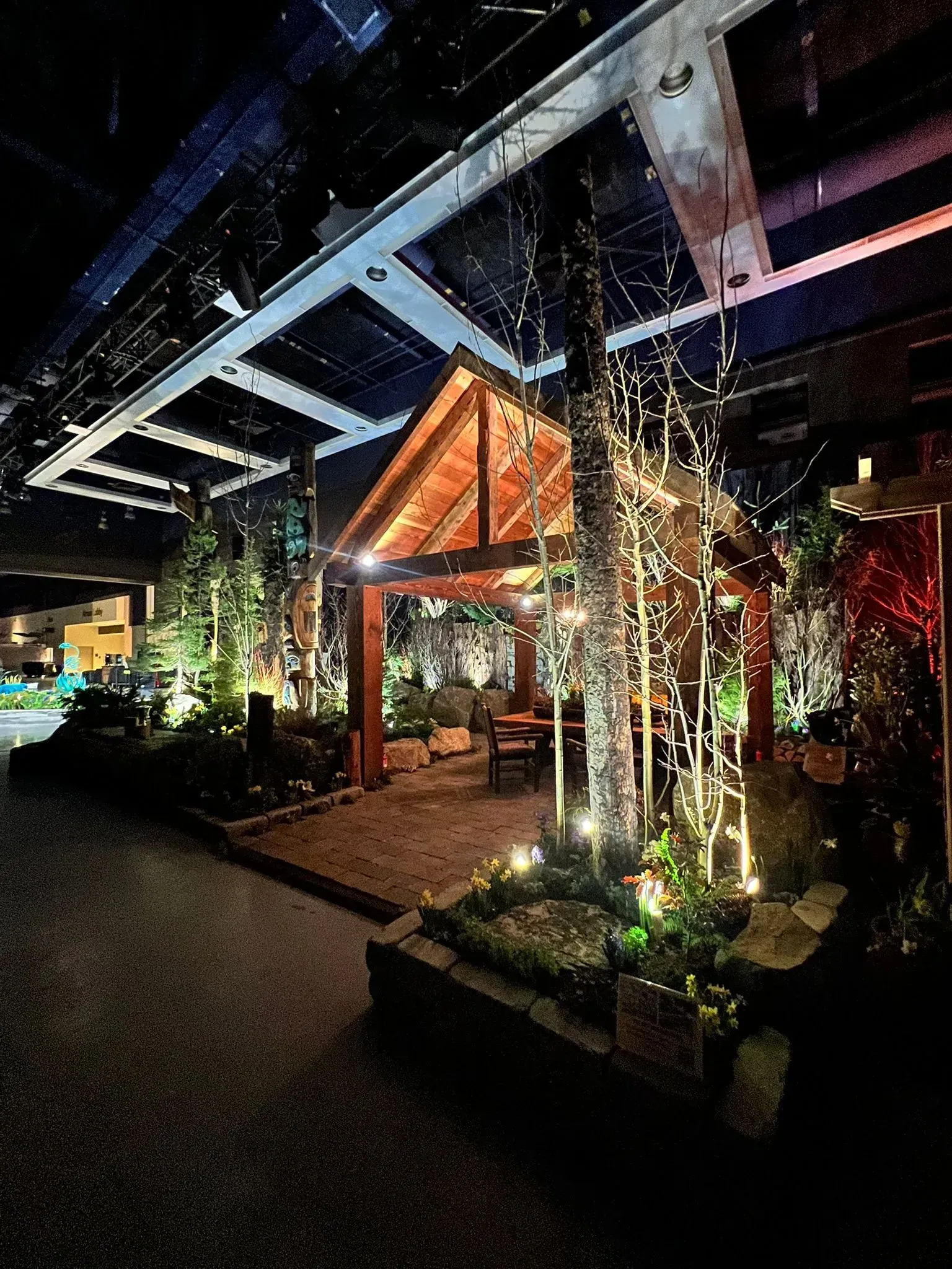 Outdoor-like seating area with a wooden gazebo and string lights in a dark, industrial space.