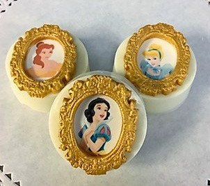 Three cookies with princess pictures on them are sitting on a table.