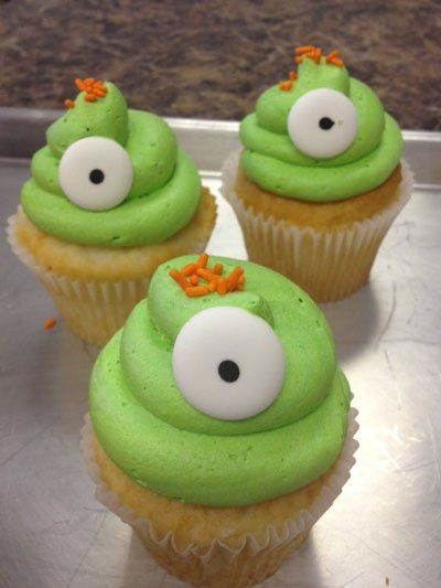 Three cupcakes with green frosting and white eyes on them