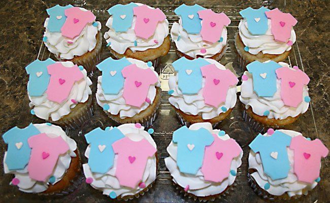 A bunch of cupcakes with baby clothes on them