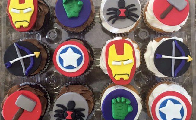 A bunch of cupcakes with avengers logos on them