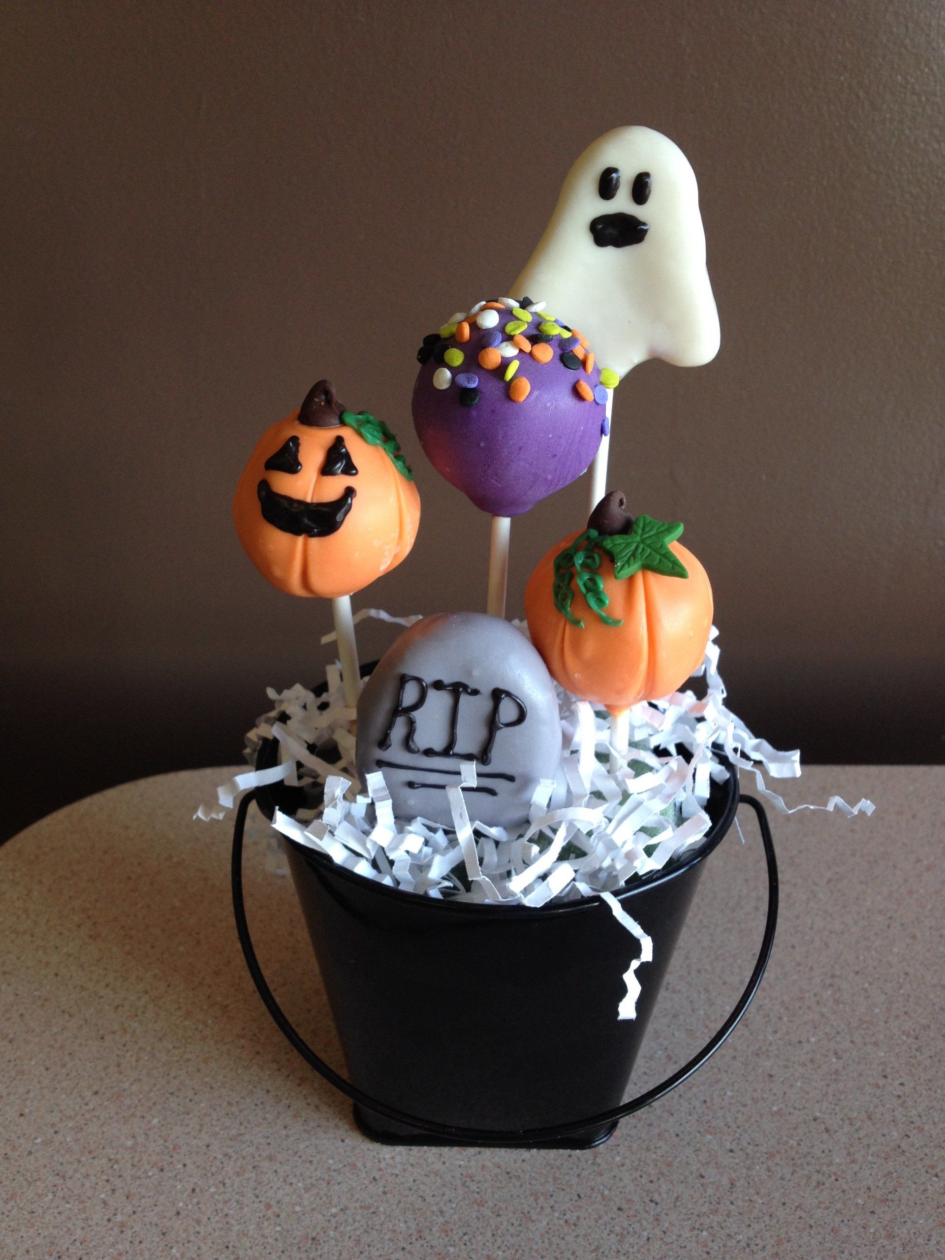 A bucket filled with halloween treats including a ghost and a tombstone that says rip