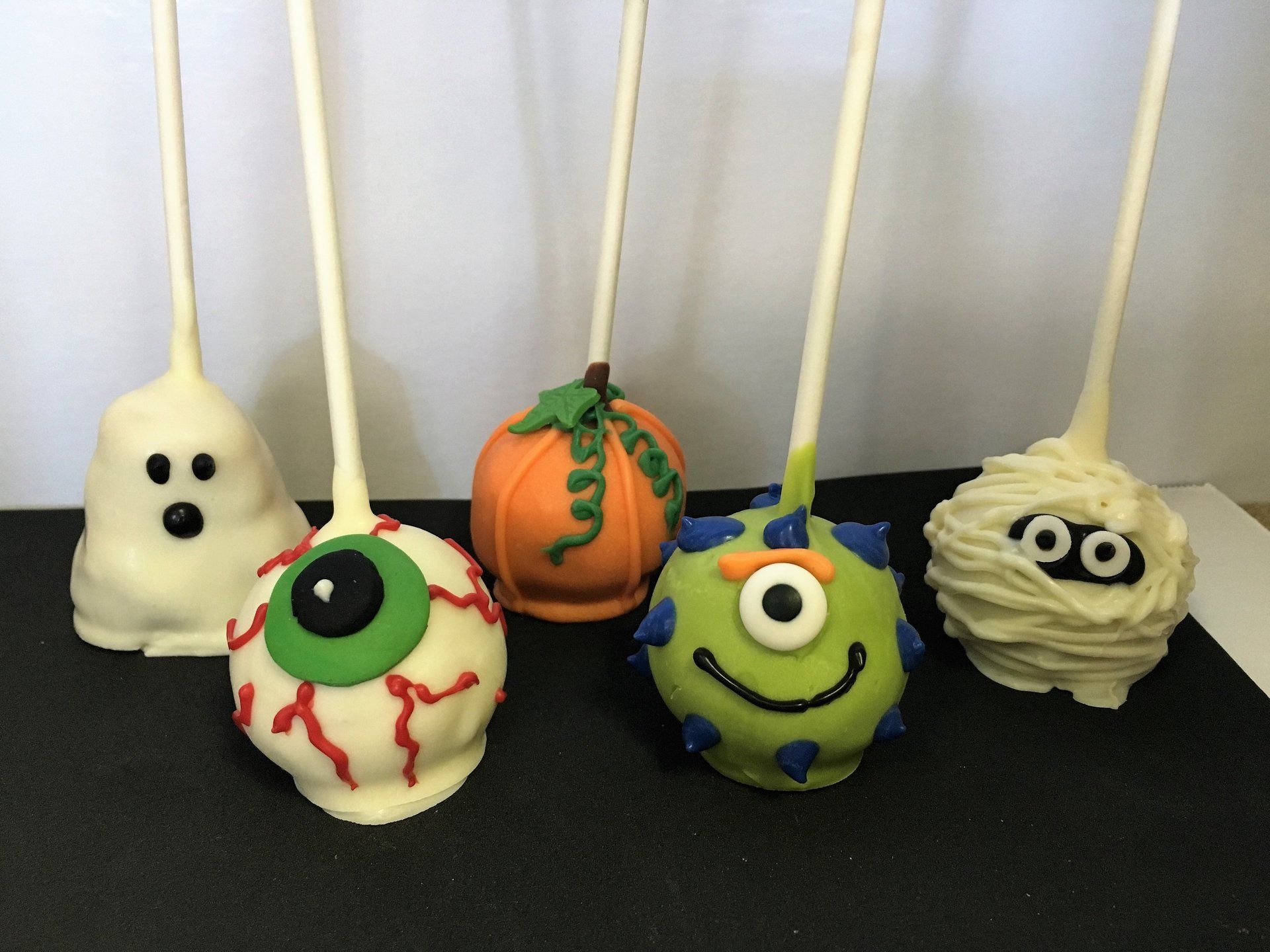 A bunch of halloween themed cake pops on a table