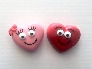 A pink heart and a red heart with faces on them