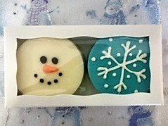 A box filled with two cookies decorated to look like snowmen and snowflakes.