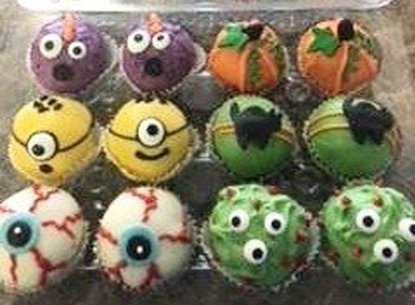 A plastic container filled with cupcakes decorated for halloween.