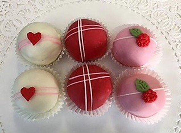 A bunch of cupcakes with hearts on them on a plate.