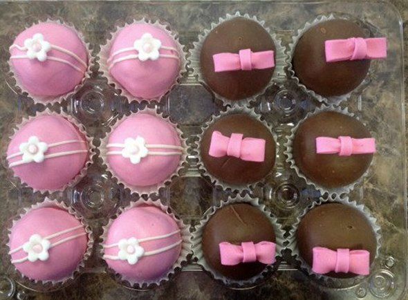 A tray of pink and brown cupcakes with bows on them