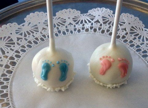 Two cake pops with blue and pink footprints on them