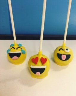 Three yellow cake pops with smiley faces on them
