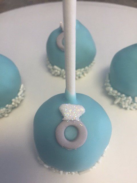 A blue cake pop with a ring on it