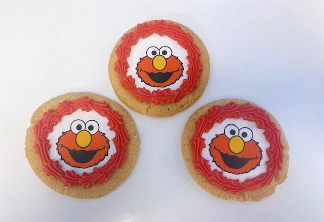 Three sesame street cookies with elmo faces on them